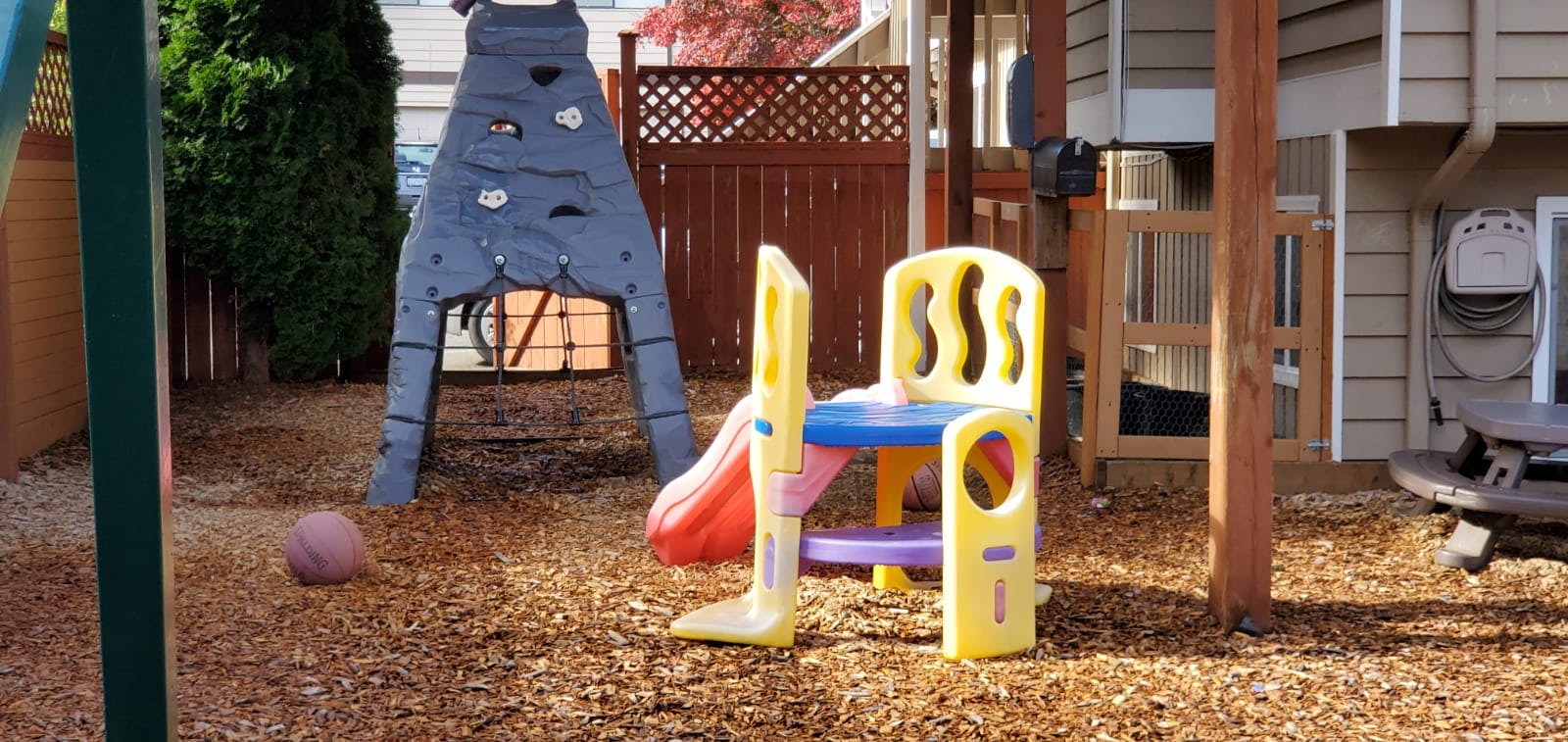 Playground with a small slide, climbing structure, and ball