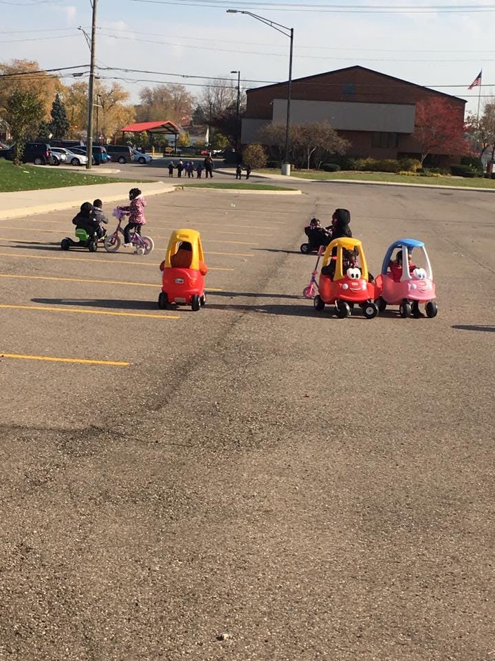 Children playing with ride-on toys and bicycles in a parking lot