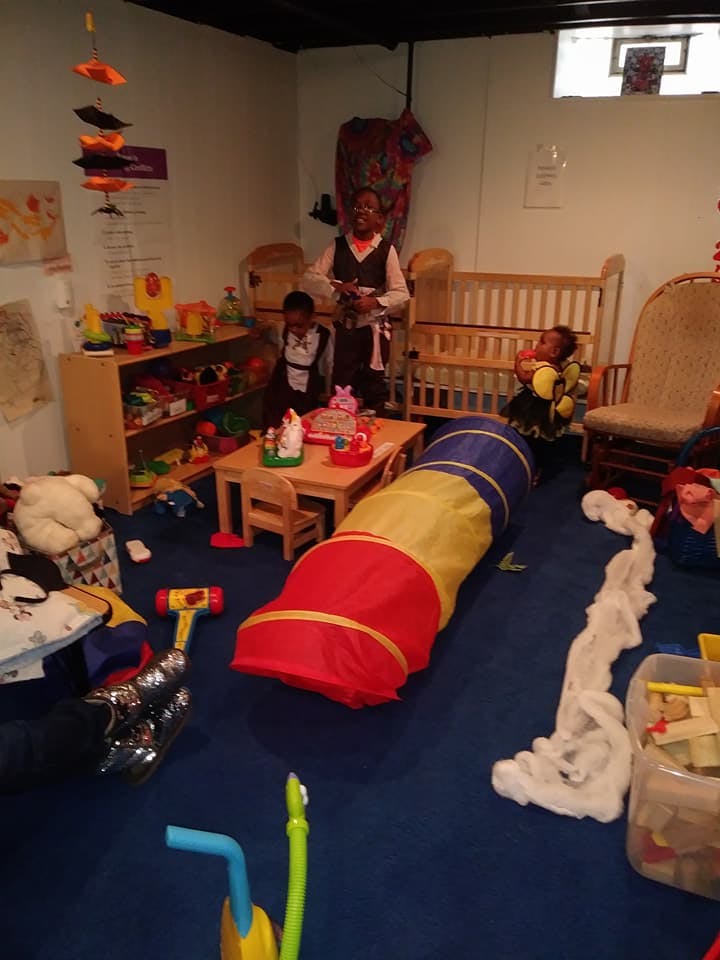 Adult and two children in a playroom with toys and a play tunnel
