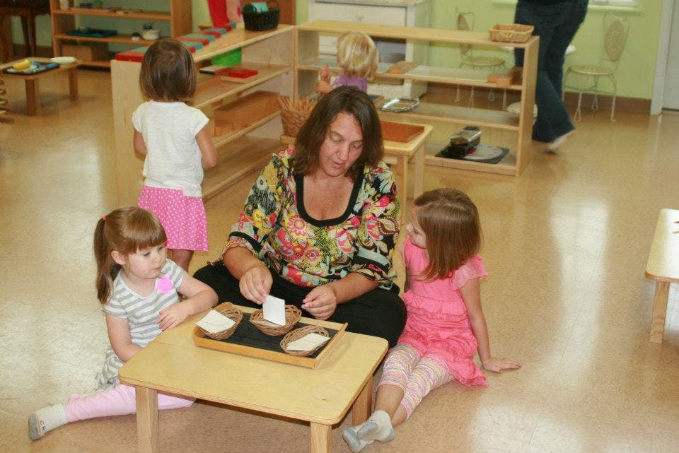 Adult and two children sitting on floor with small table and activity