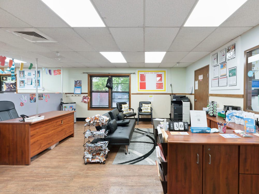 Office space with desks, a couch, chairs, and multiple wall decorations