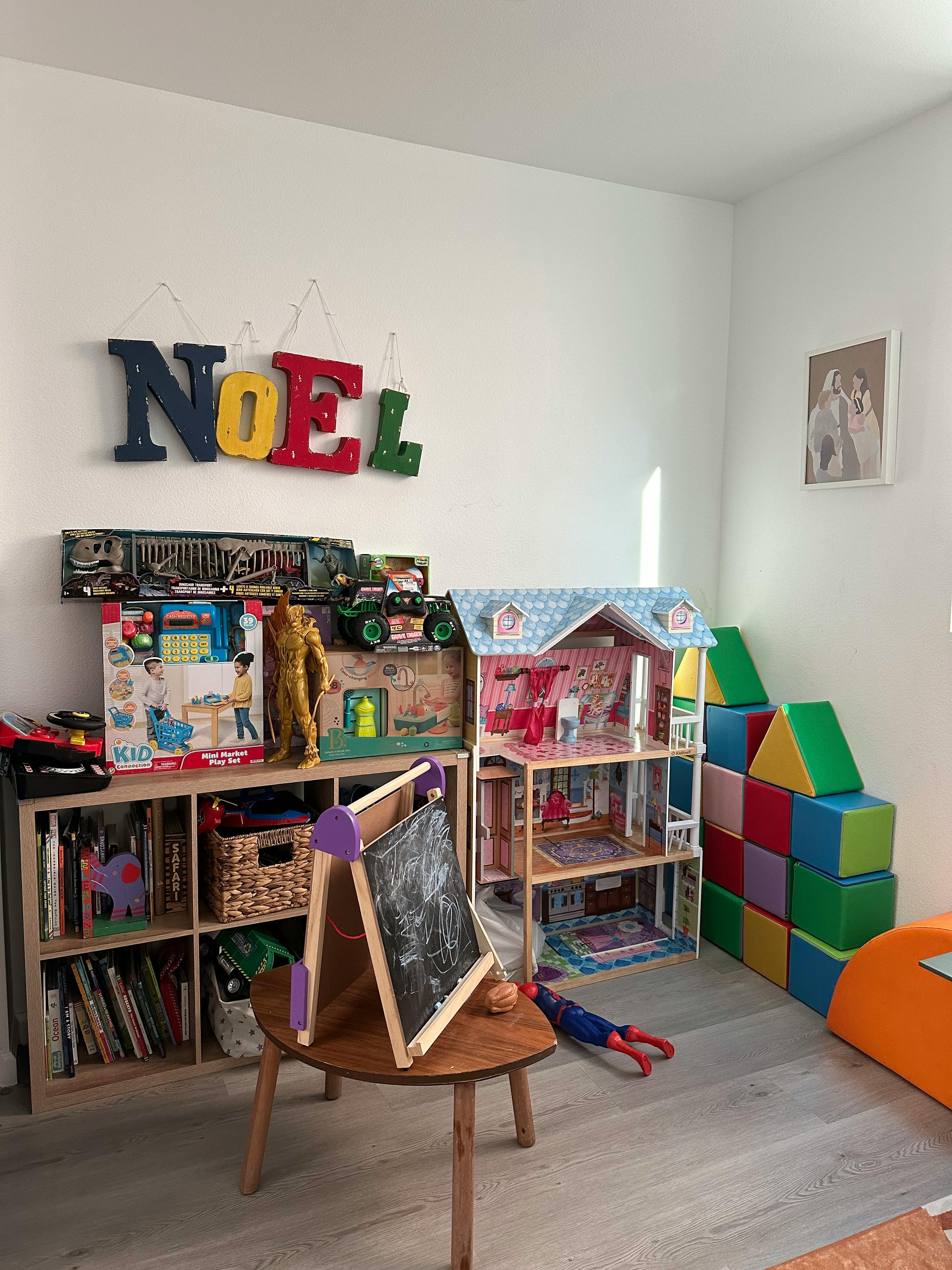 Playroom with a dollhouse, bookshelf, chalkboard easel, and soft blocks