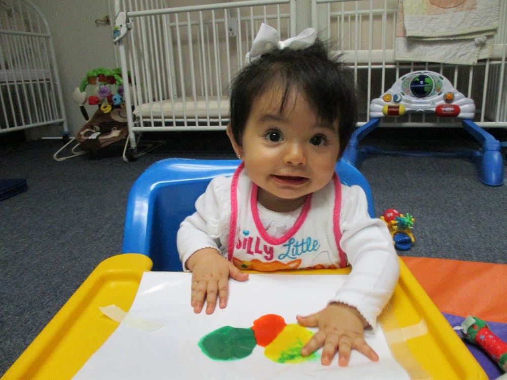 Child in high chair with paint on paper