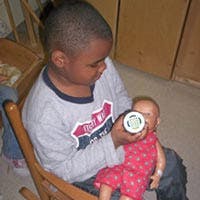 Child feeding a doll with a bottle