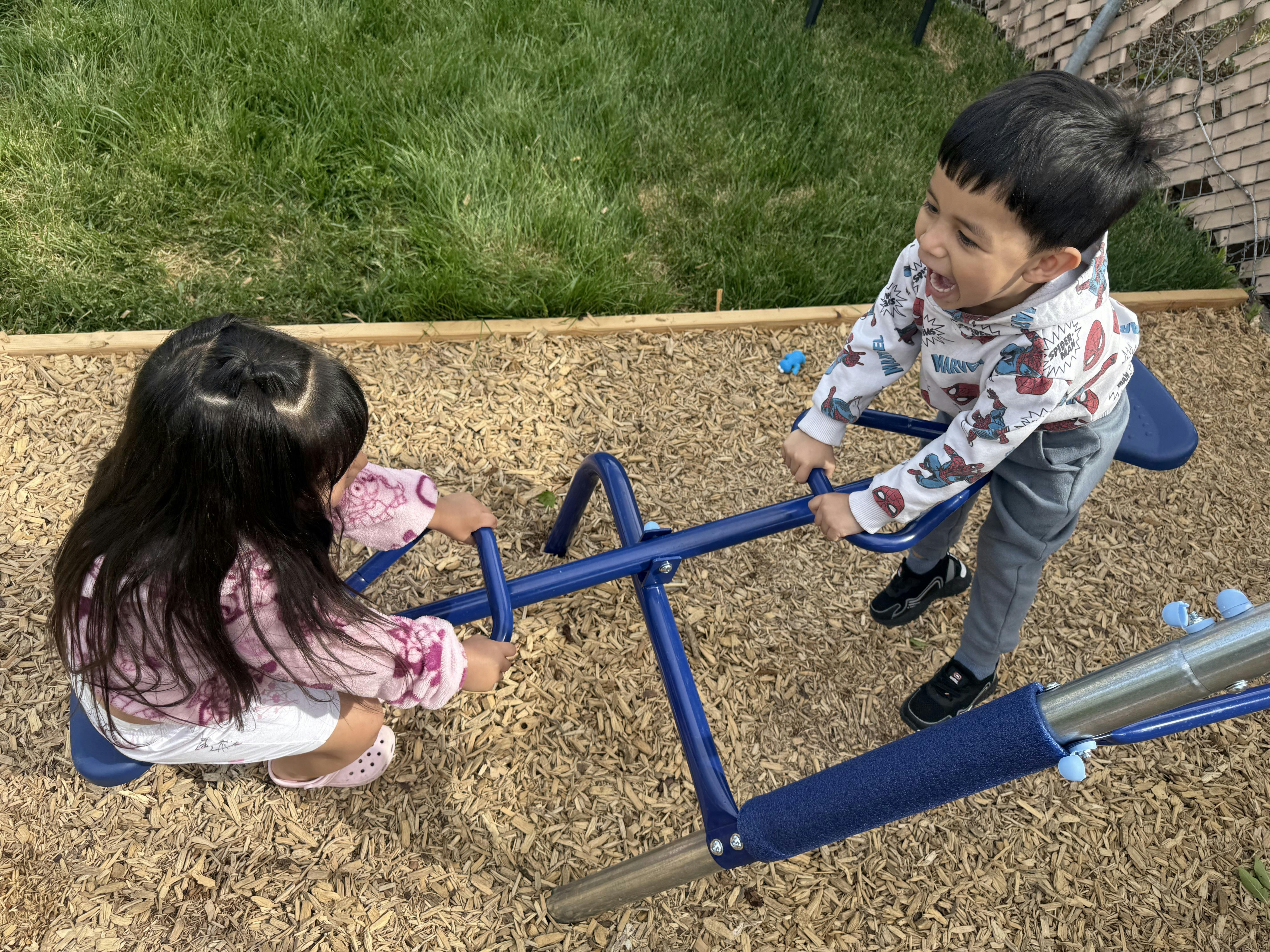 Two children on a seesaw at a playground