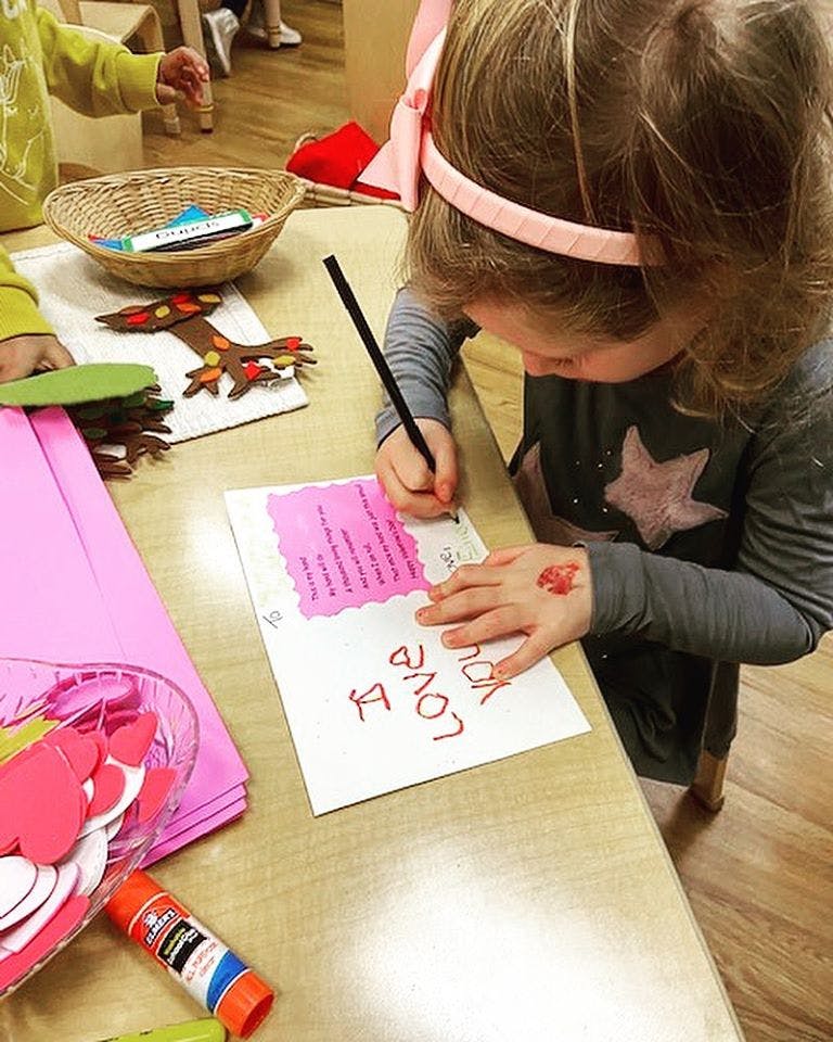 Child writing on a card at a table