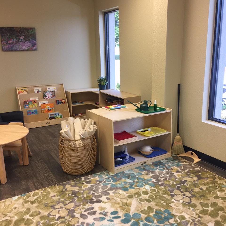 Classroom with small tables, shelves, and a colorful rug