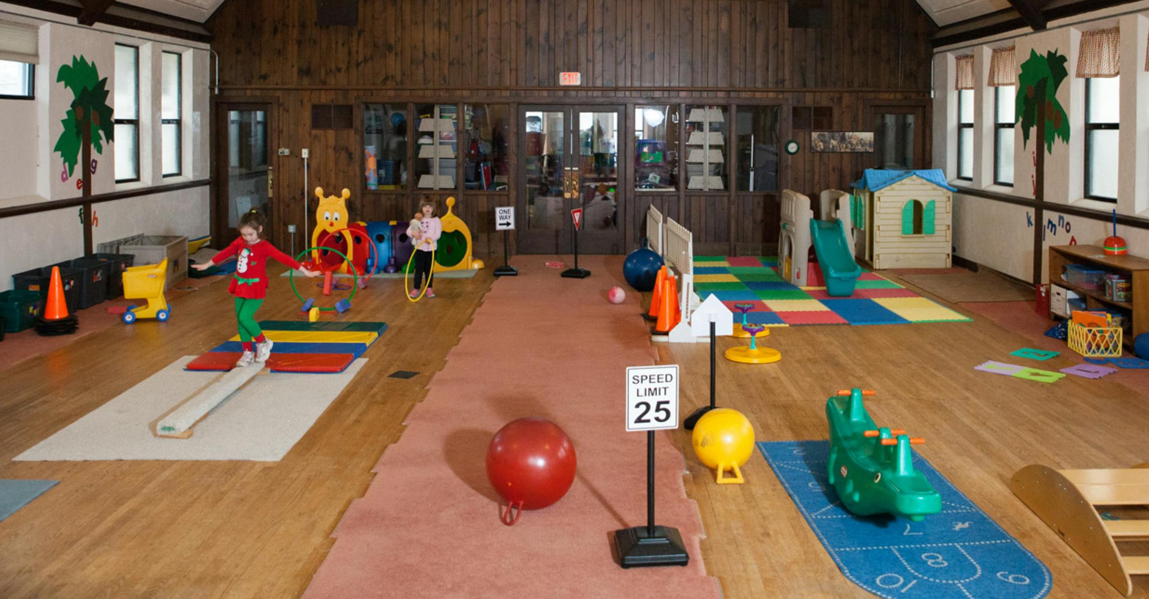 Children playing in a large room with various play equipment