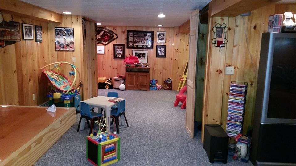 Finished basement with wood paneling, carpet, and various furniture and toys
