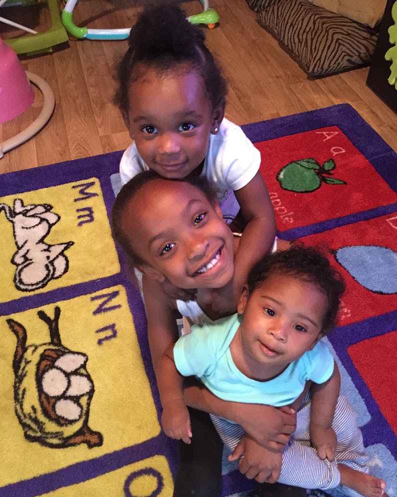 Three children posing on an alphabet rug