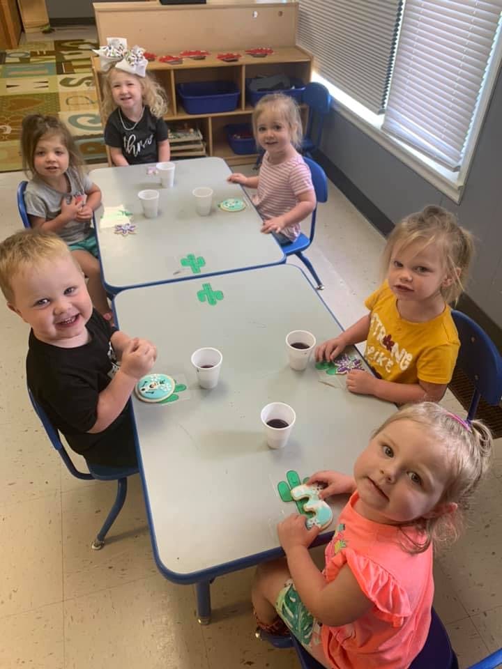 Children sitting at tables with cups and crafts