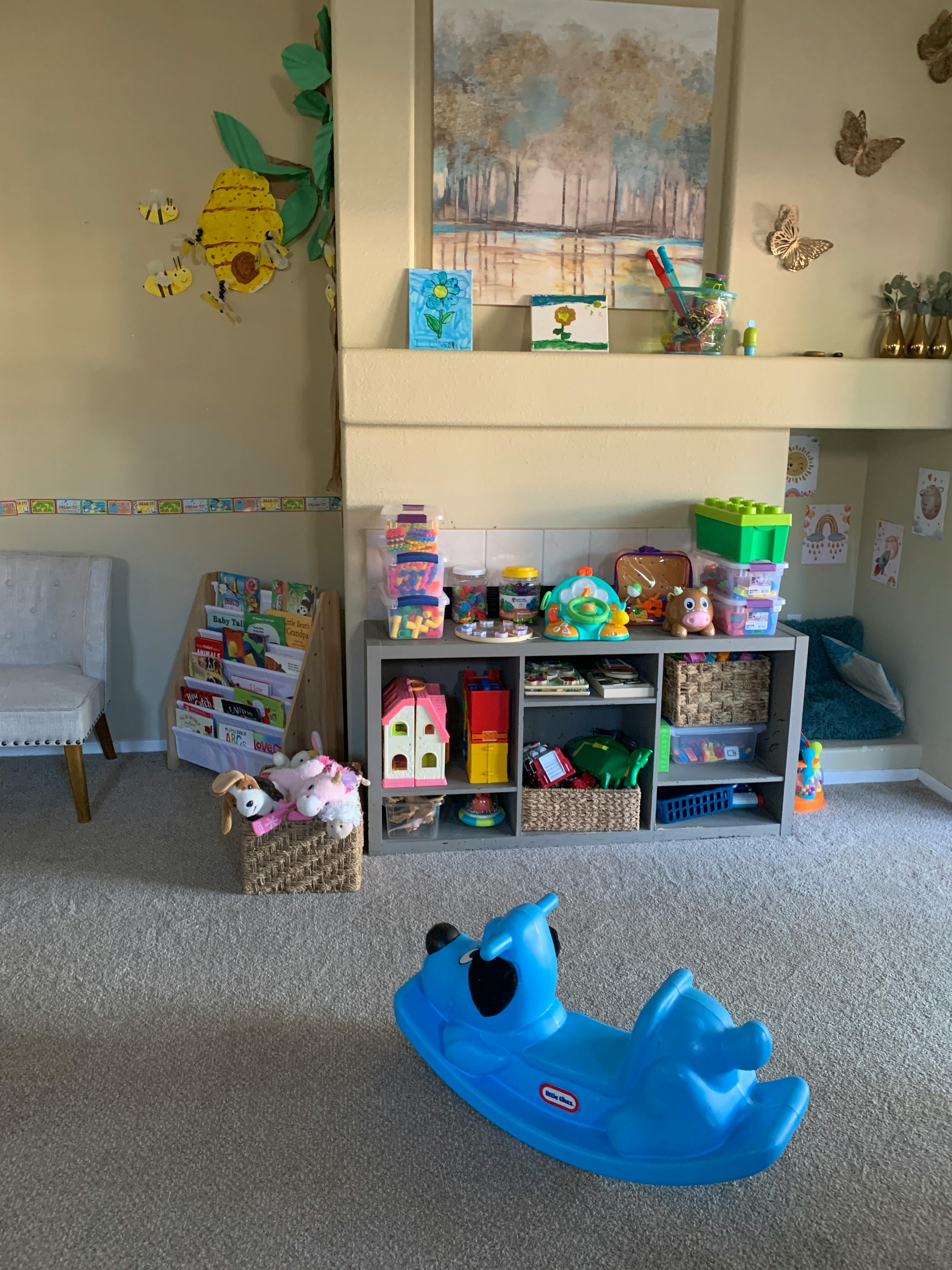 Playroom with a blue rocking toy, shelves of toys, and wall decorations