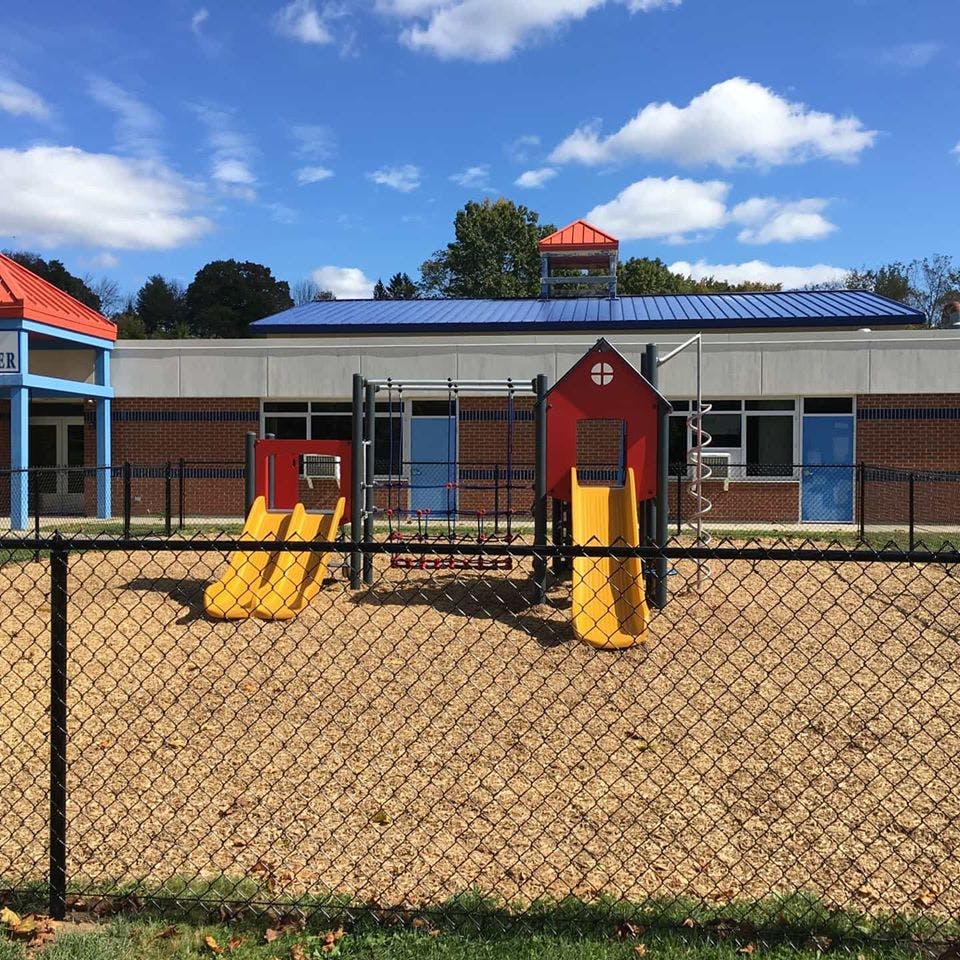 Playground with yellow slides and red structures in front of a building