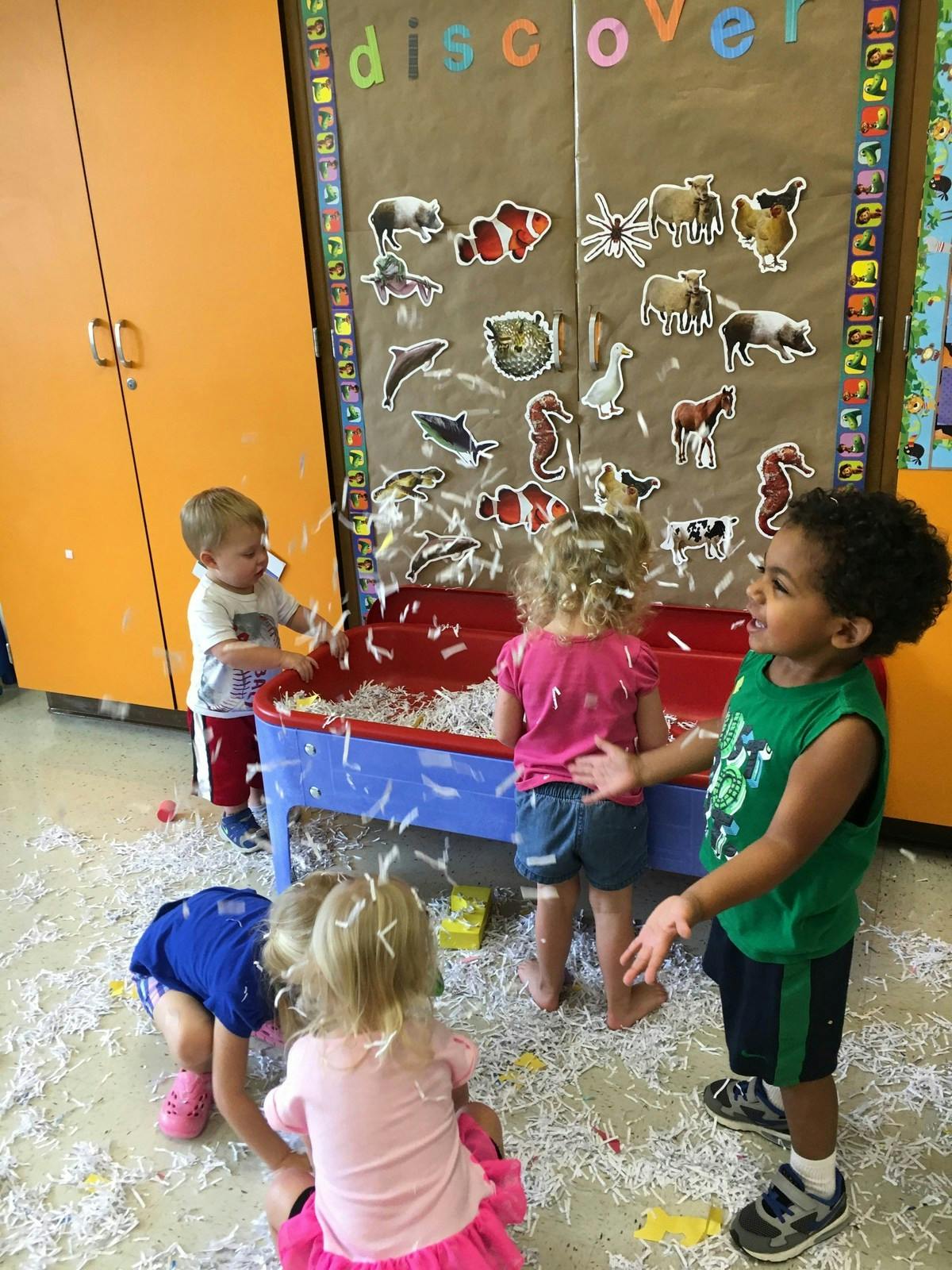 Children playing with shredded paper in a classroom