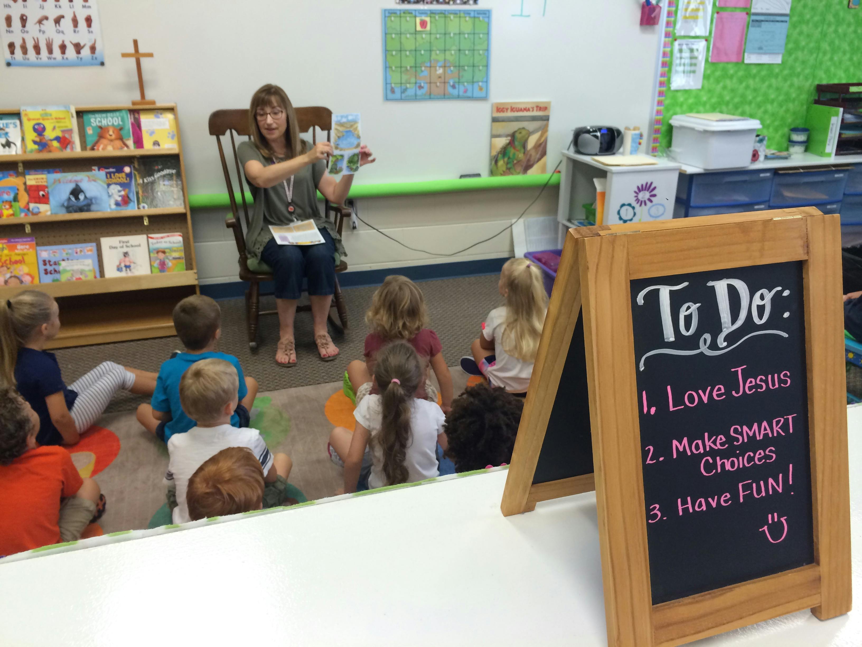 Person reading a book to children sitting on the floor in a classroom