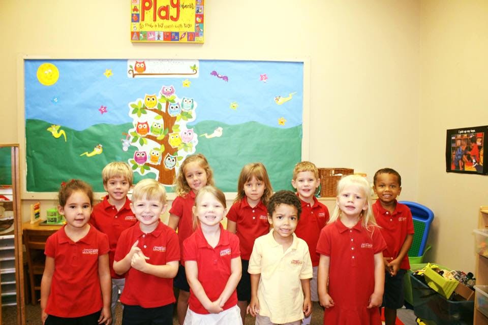 Group of children standing in a classroom in front of a bulletin board
