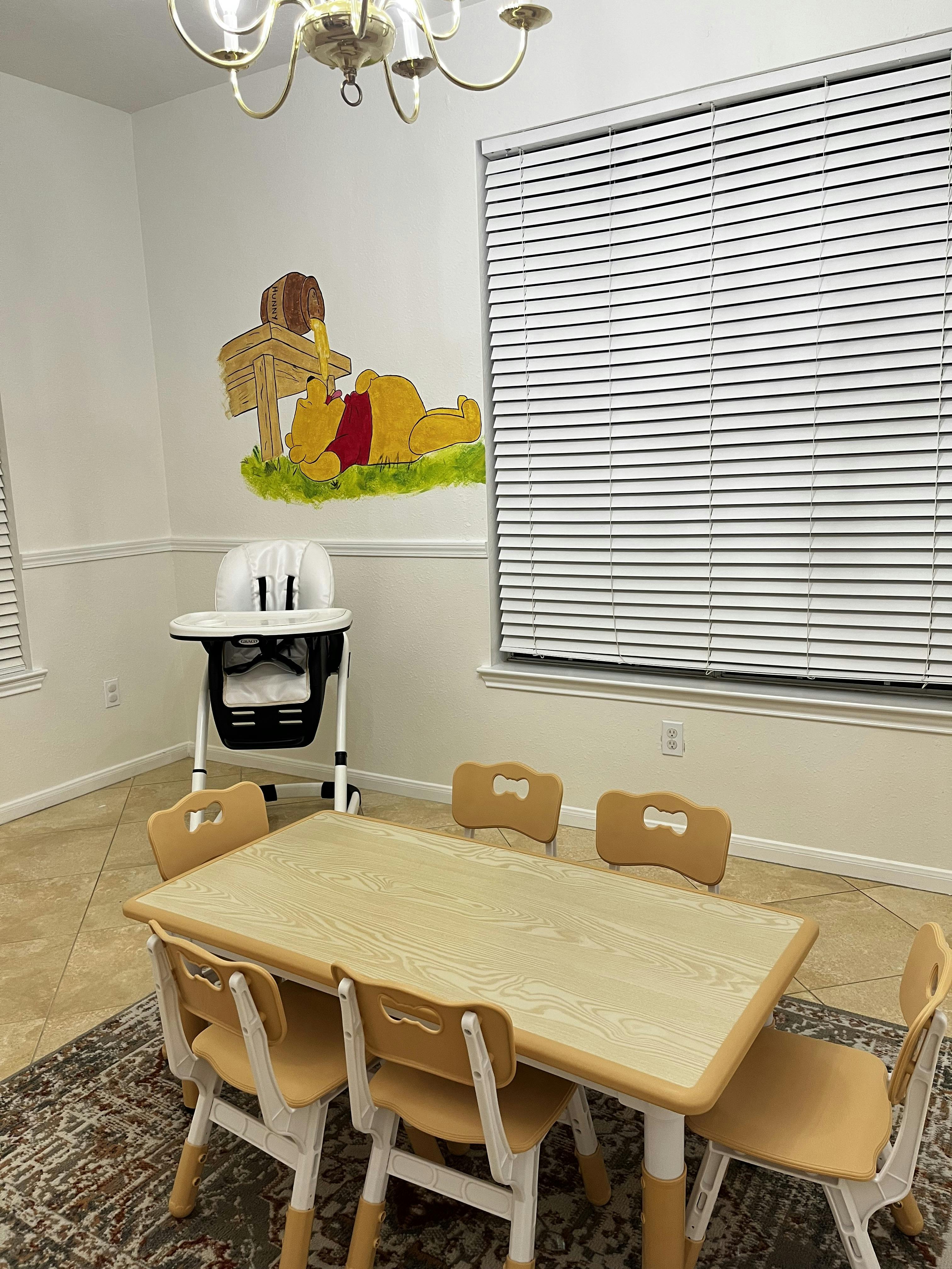Child's table and chairs with a high chair and Winnie the Pooh wall decal