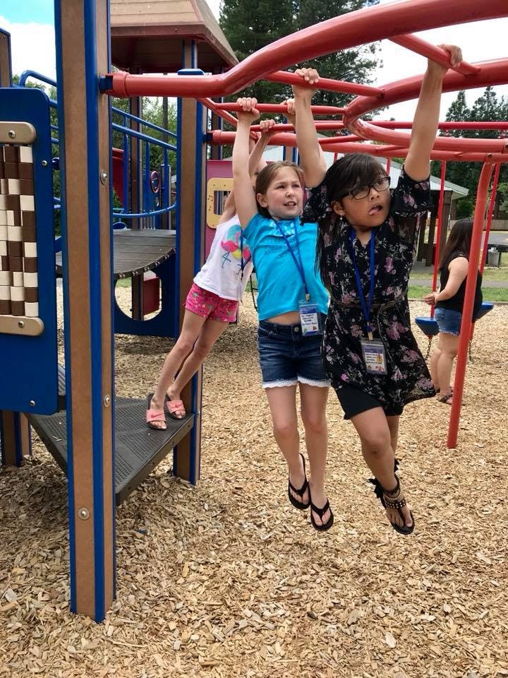 Three children playing on monkey bars at a playground