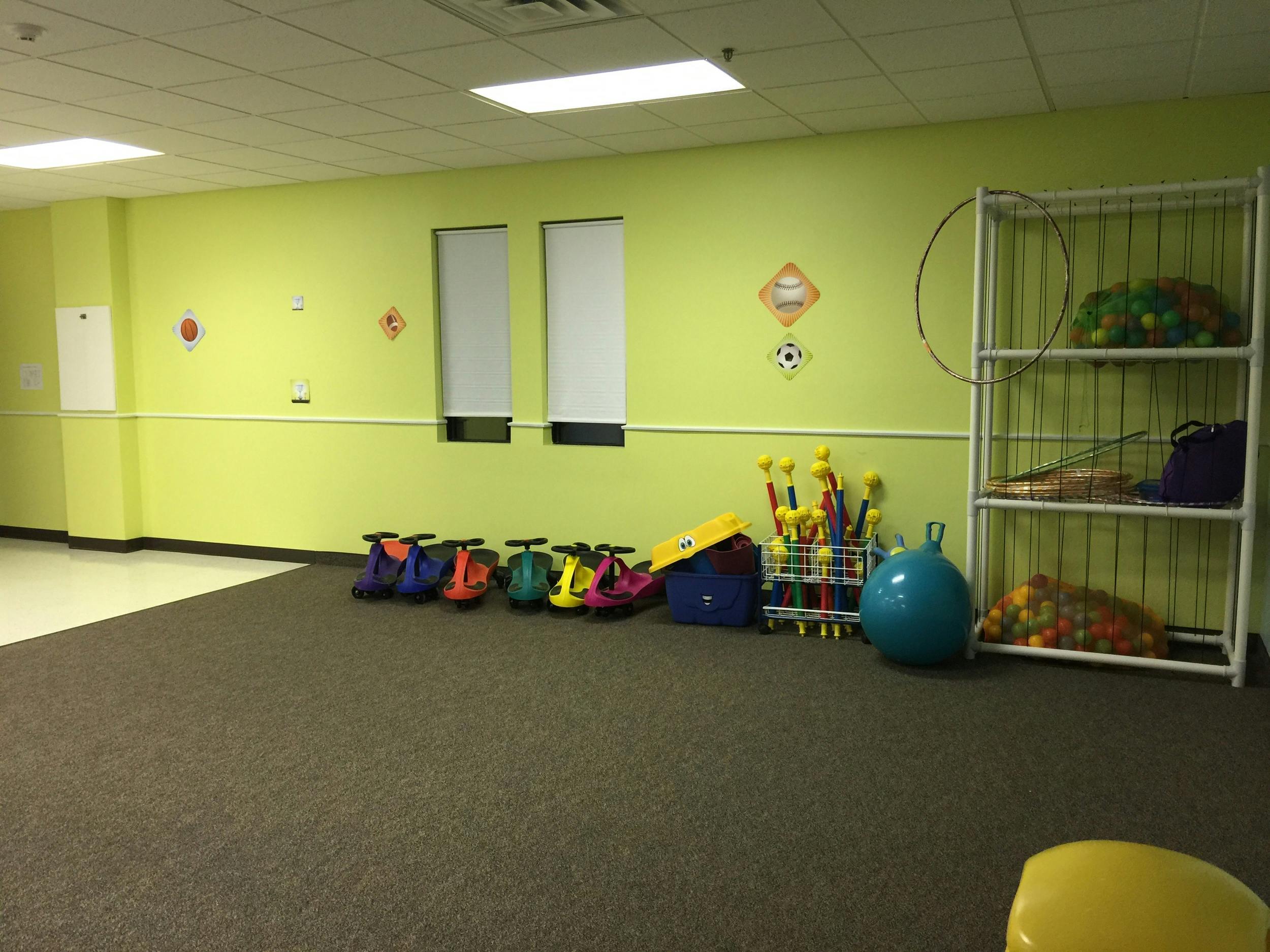 Indoor play area with small ride-on toys, shelves, and exercise ball