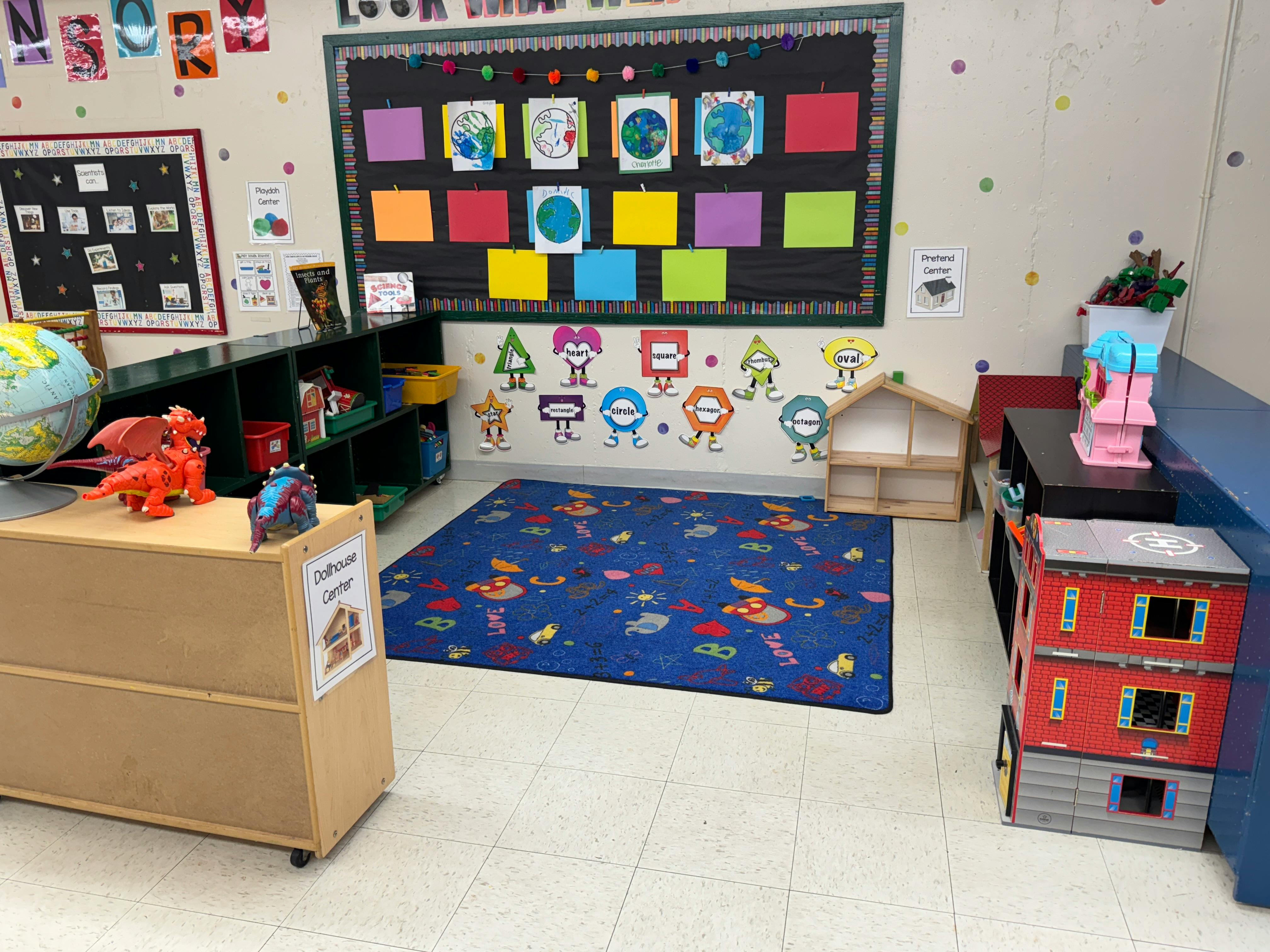 Classroom with a blue rug, bulletin board, and toys