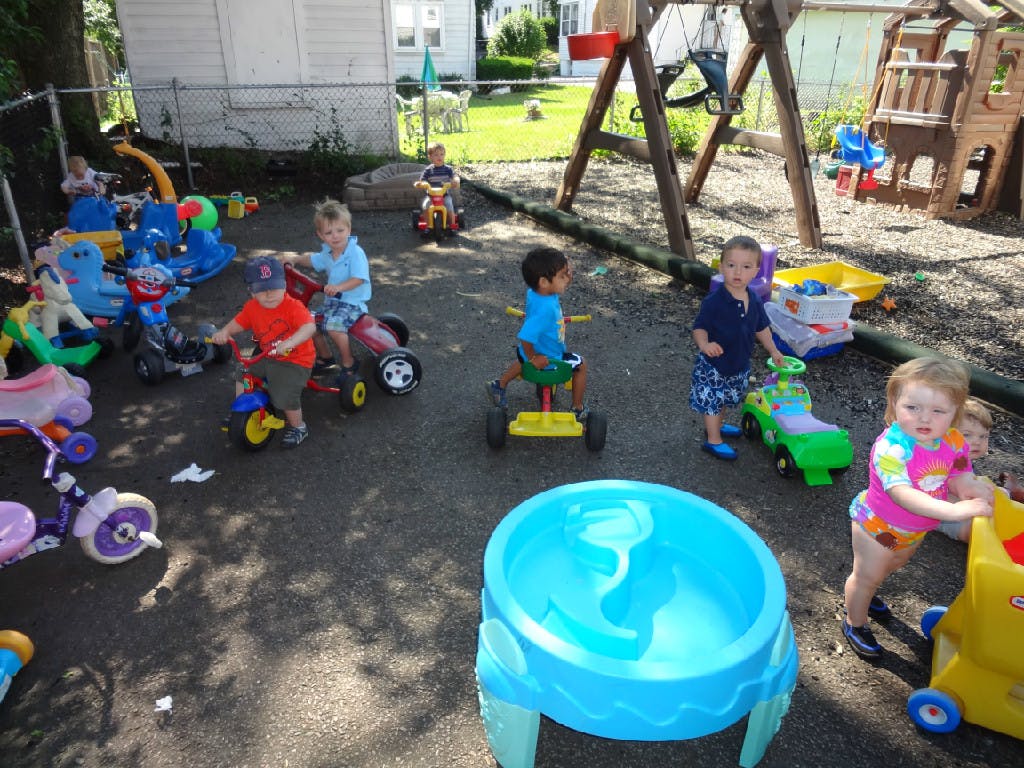 Children playing with ride-on toys in a paved outdoor area