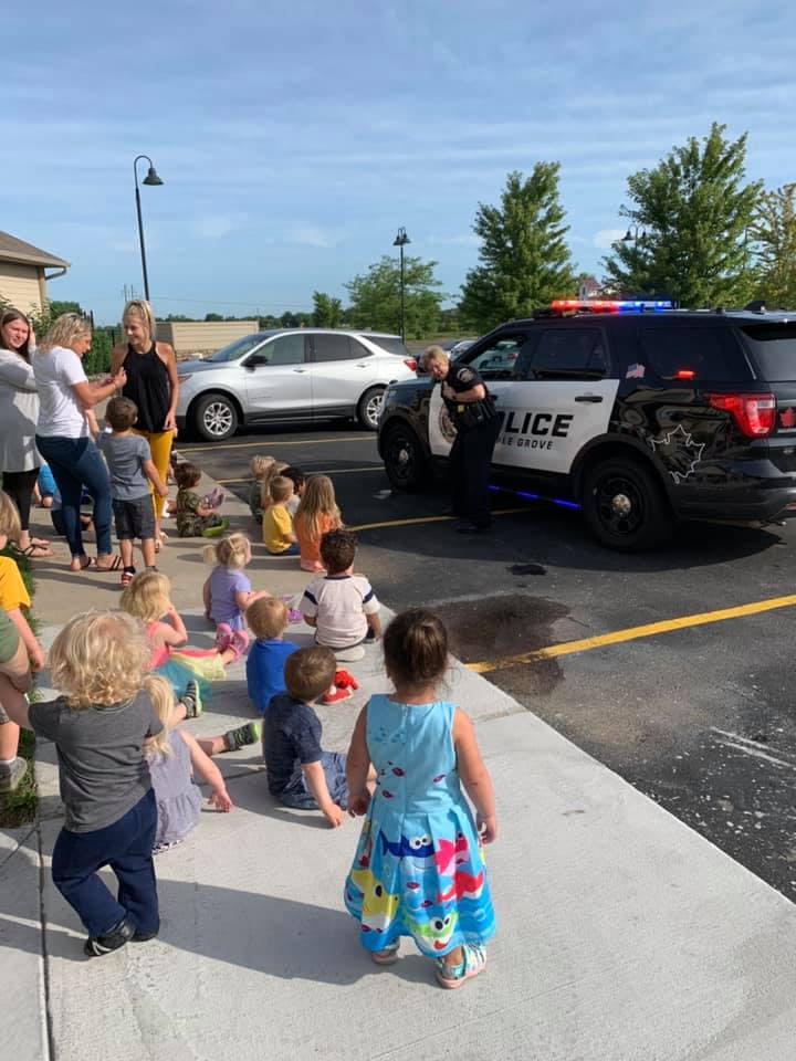 Children and adults gathered around a police car