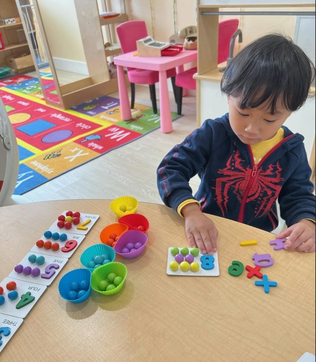 Child playing with colorful counting toys at a table