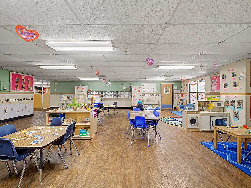 Empty colorful preschool classroom with small tables and chairs