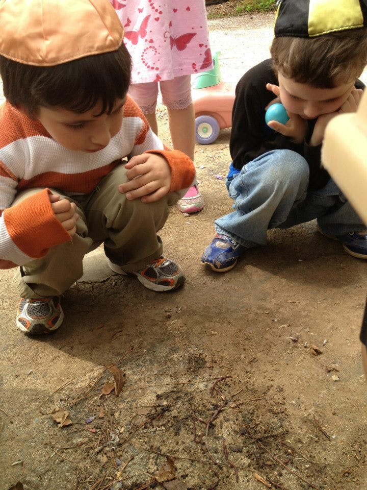 Two children crouching and looking at the ground