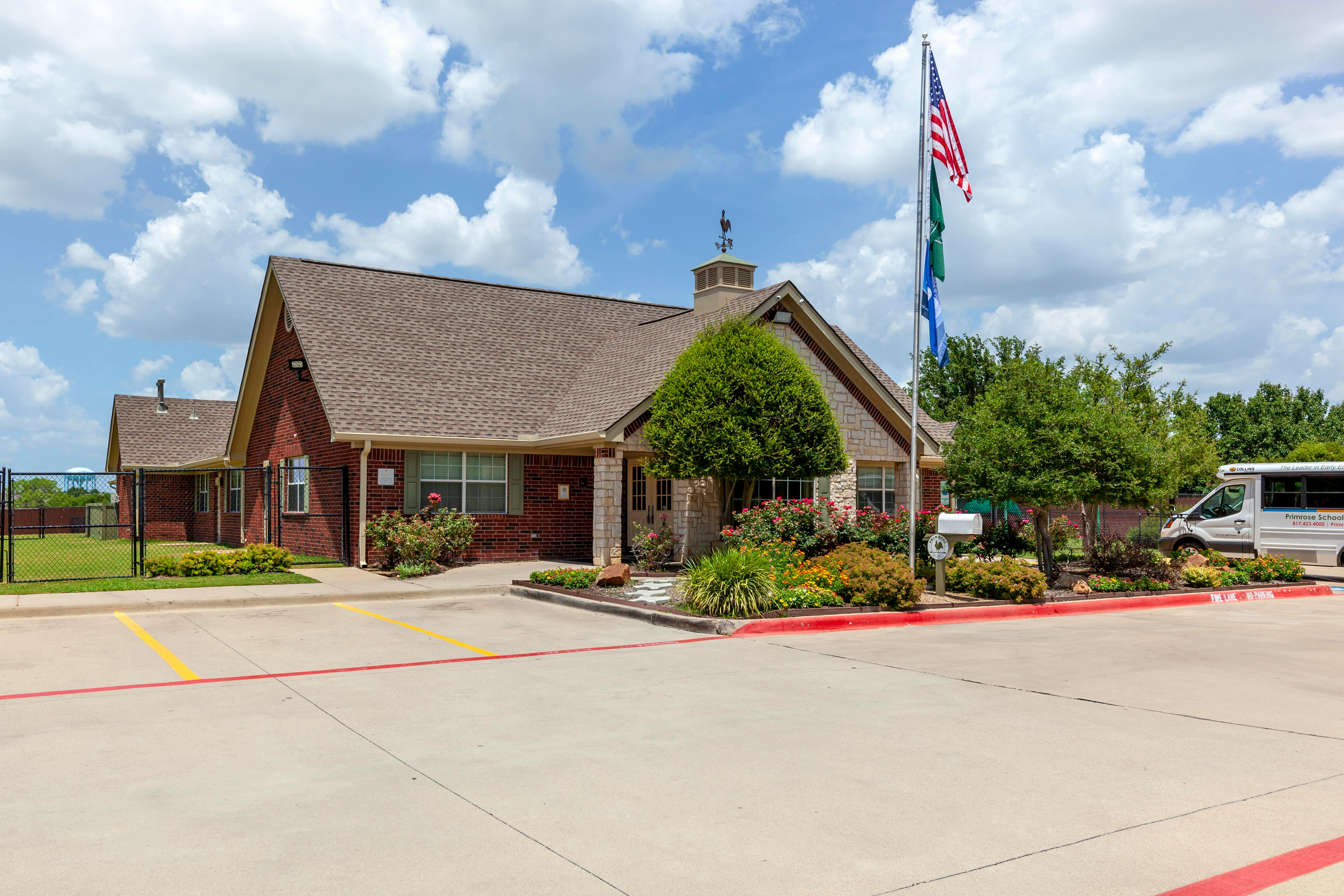 Brick building with a flagpole displaying American and green flags
