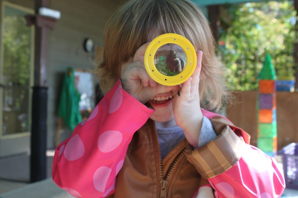 Child looking through a yellow magnifying glass