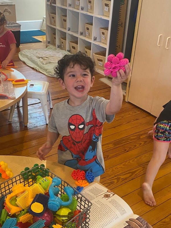 Child holding up a pink spiky toy