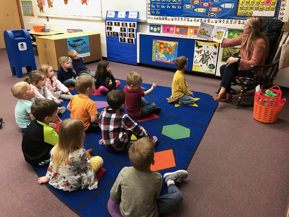 Adult reading a book to children in a classroom