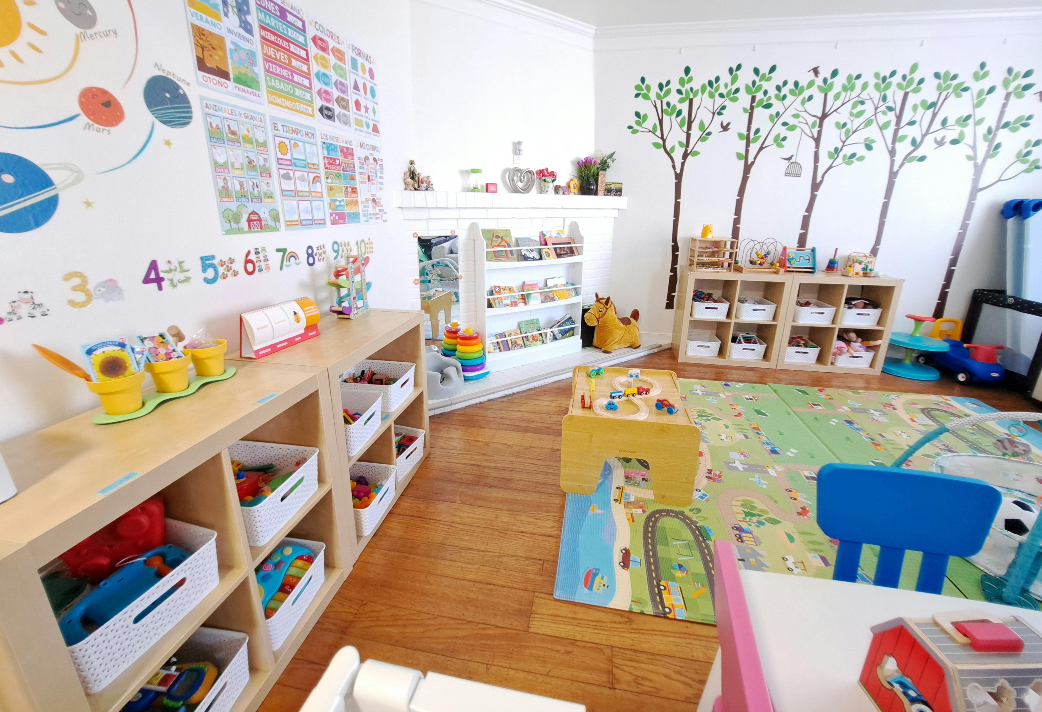 Playroom with shelves of toys, colorful rug, and tree decals on the wall