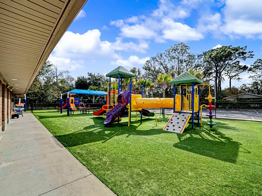 Colorful playground with slides, tunnels, and climbing features on artificial turf