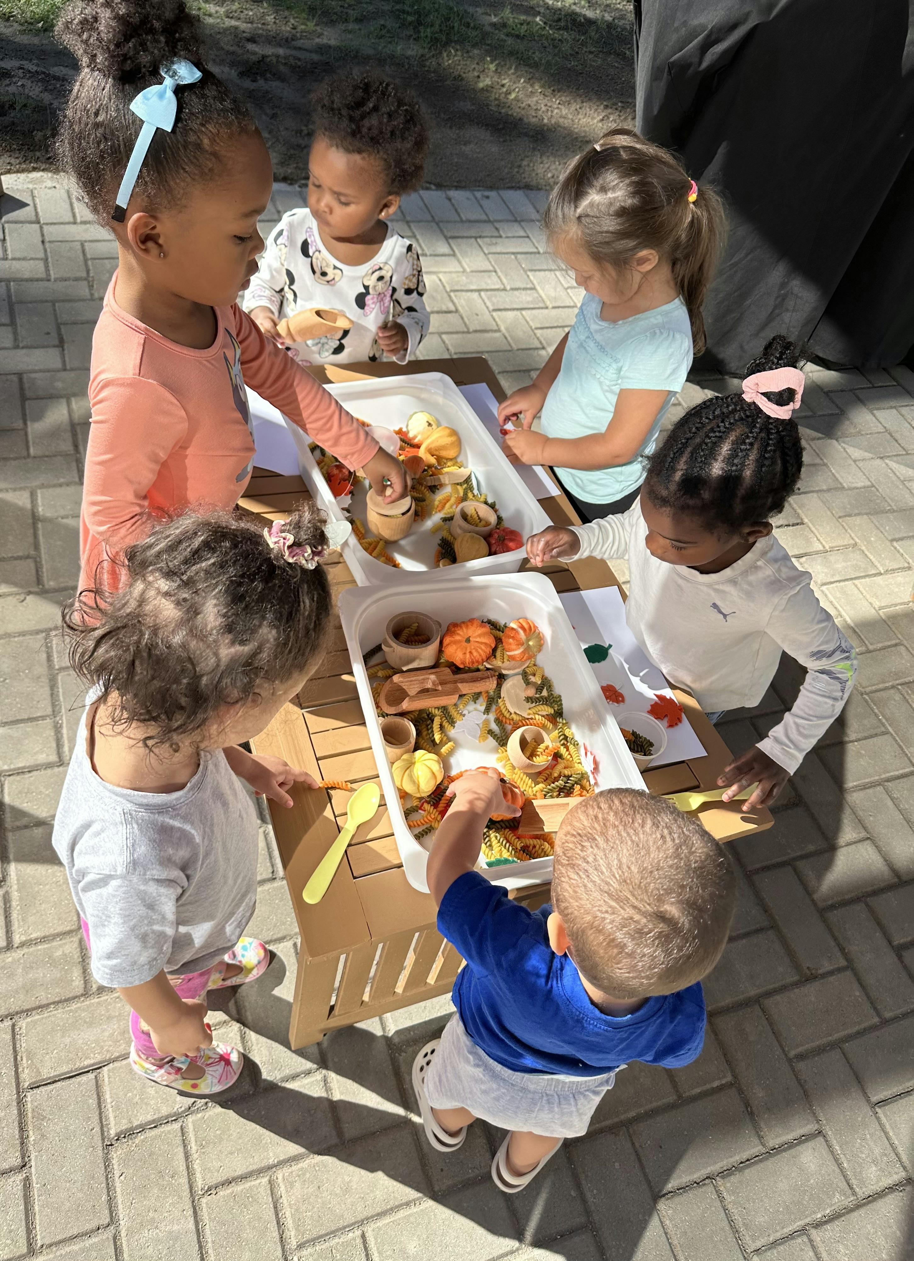Children playing with sensory bins outdoors