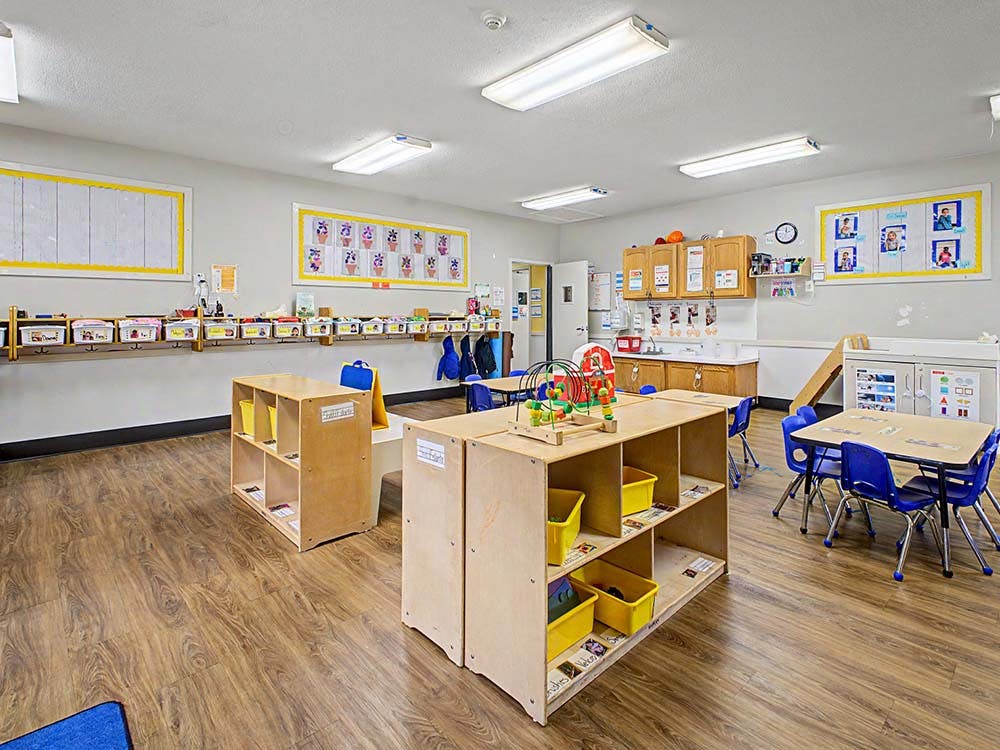 Empty classroom with small tables, chairs, and learning materials