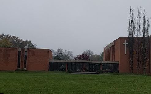 Brick building with a white cross on the side and a covered walkway