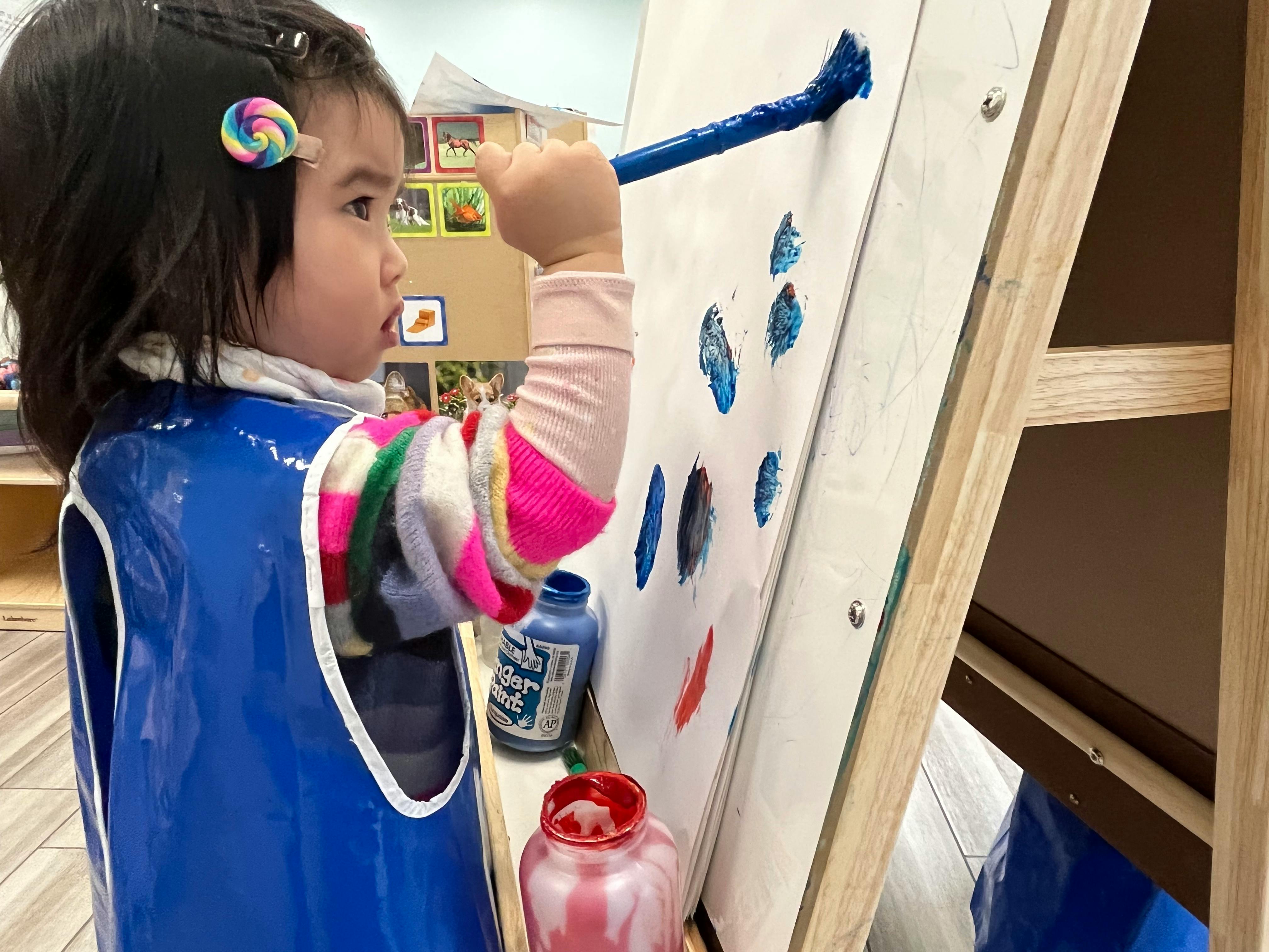 Child painting on an easel in a classroom