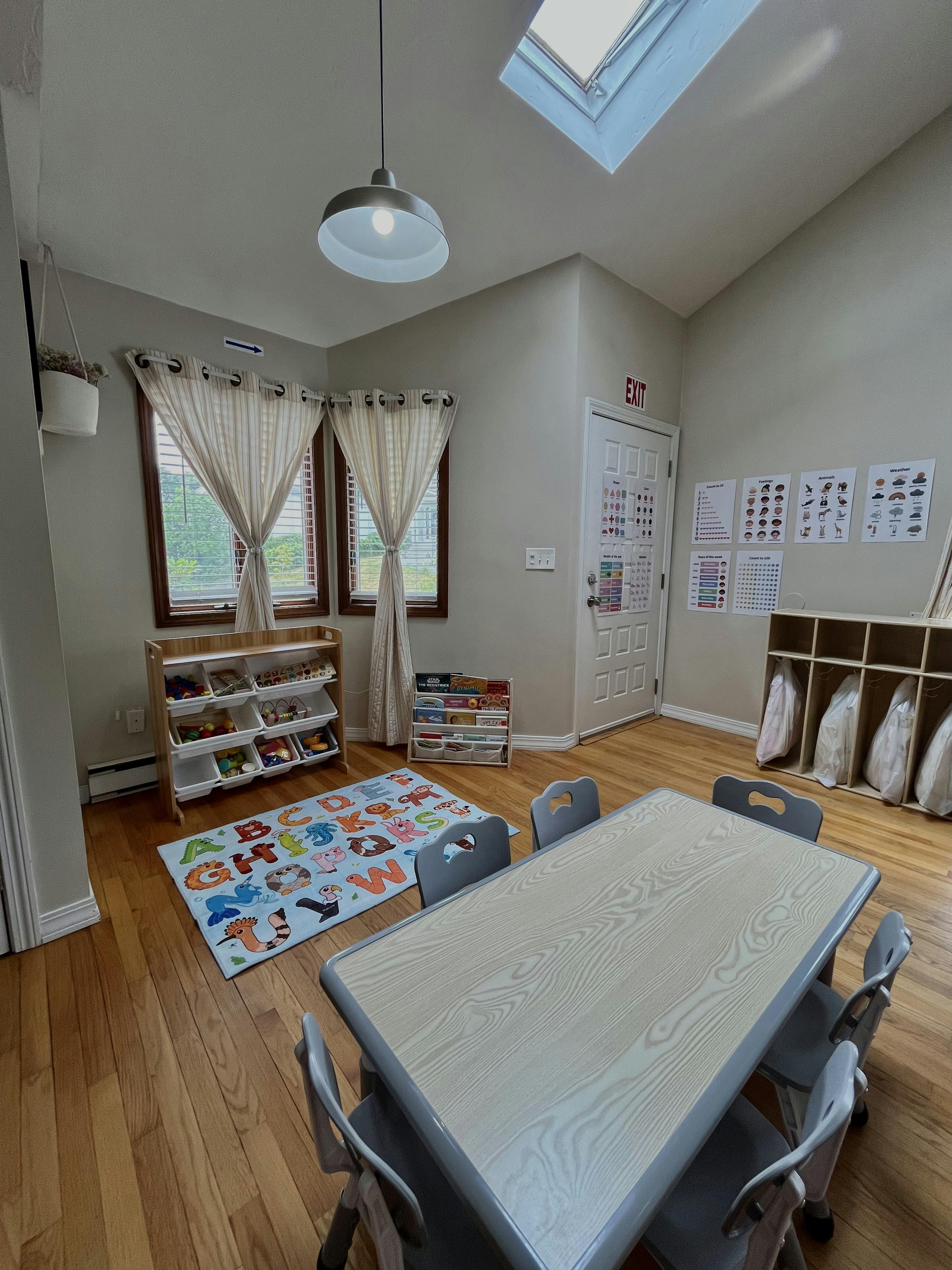 Classroom with a table and chairs, an alphabet rug, and bookshelves