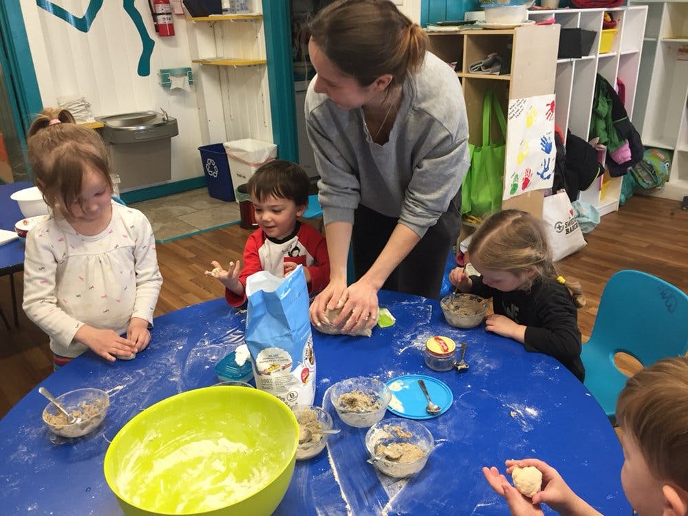 Adult and children making dough at a table