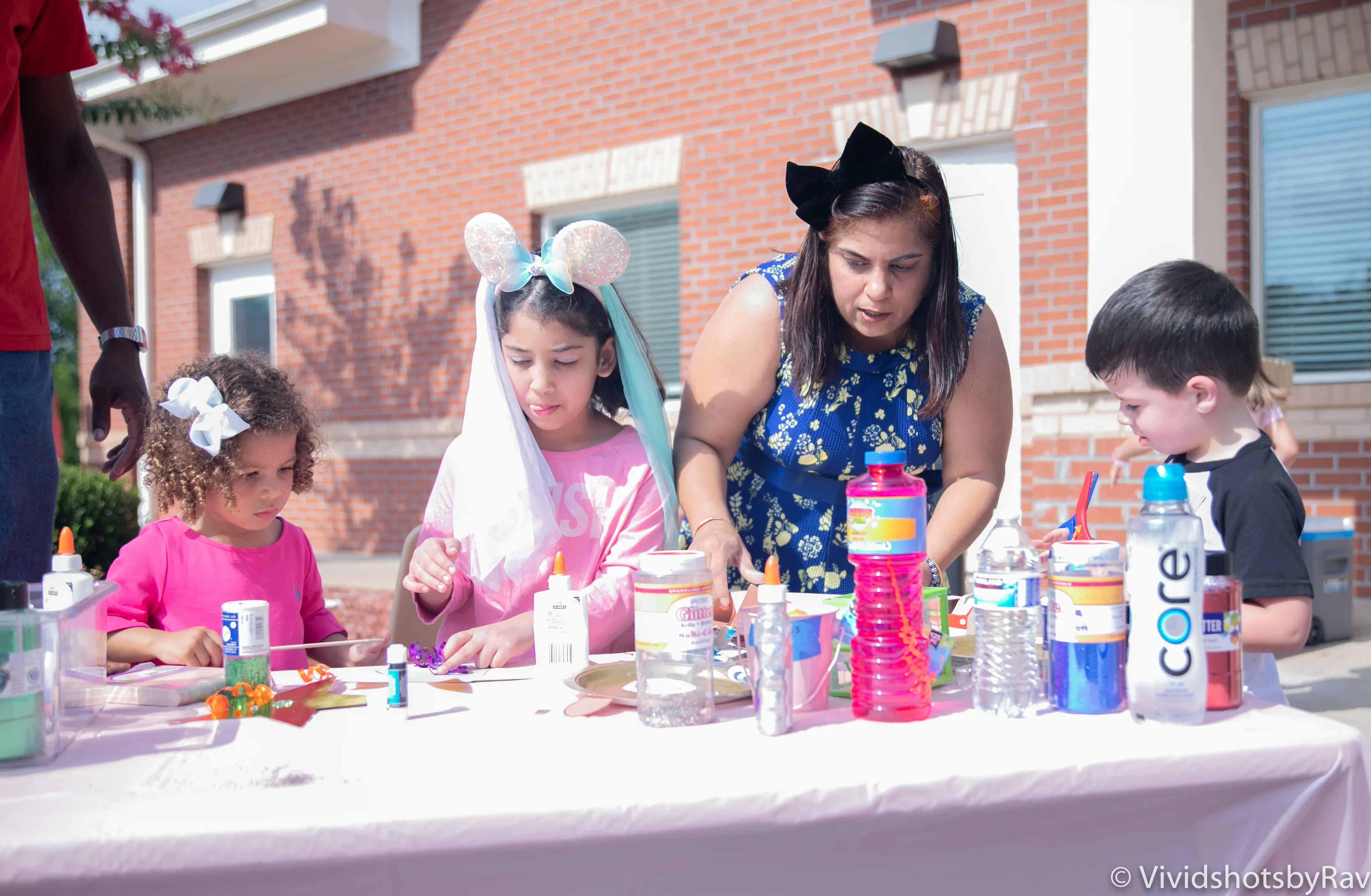 Adult and three children at a table with craft supplies