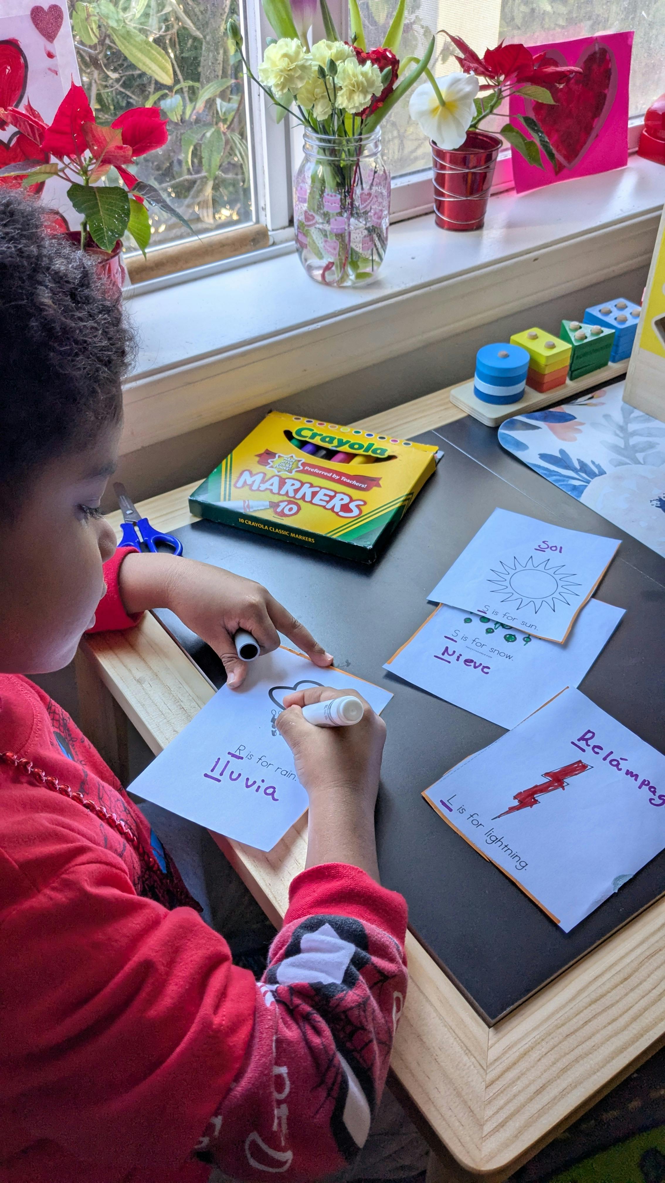 Child drawing on paper with a marker at a desk