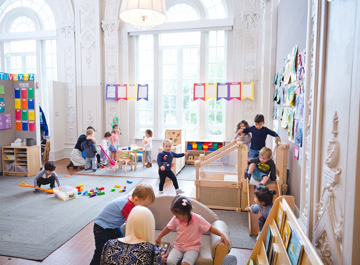 Adults and children playing with toys in a bright room