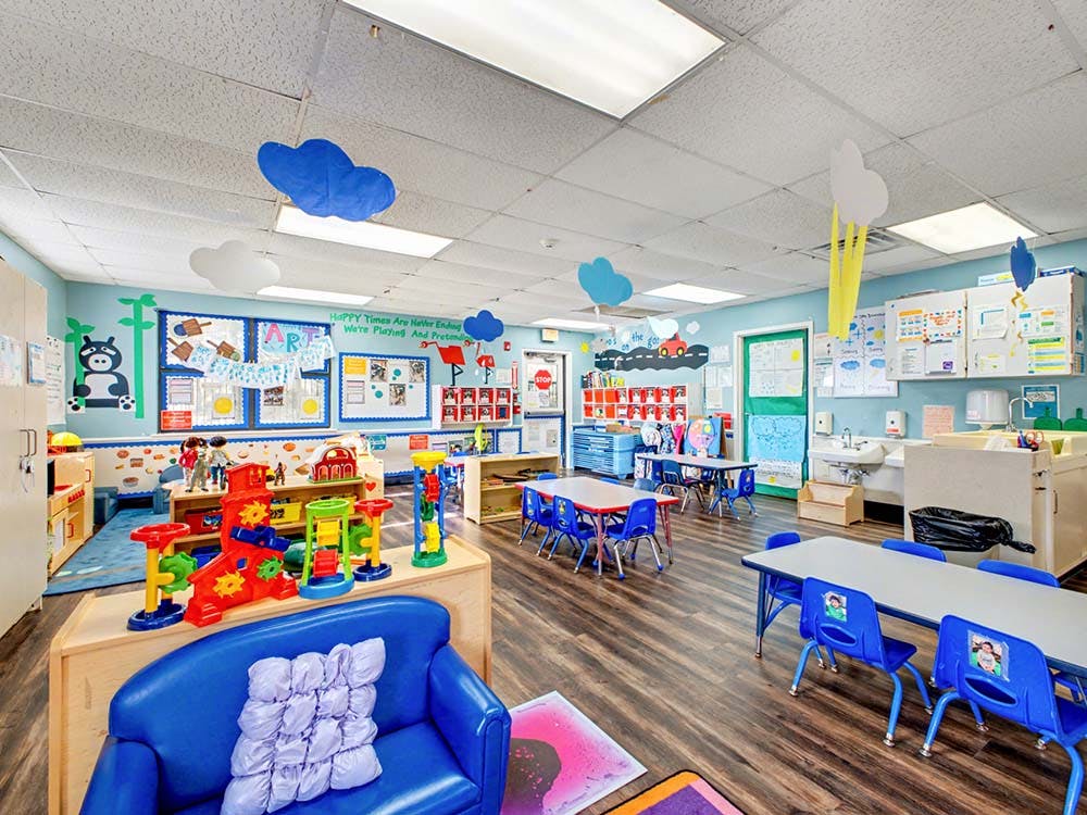 Colorful classroom with blue walls, tables, chairs, and play equipment
