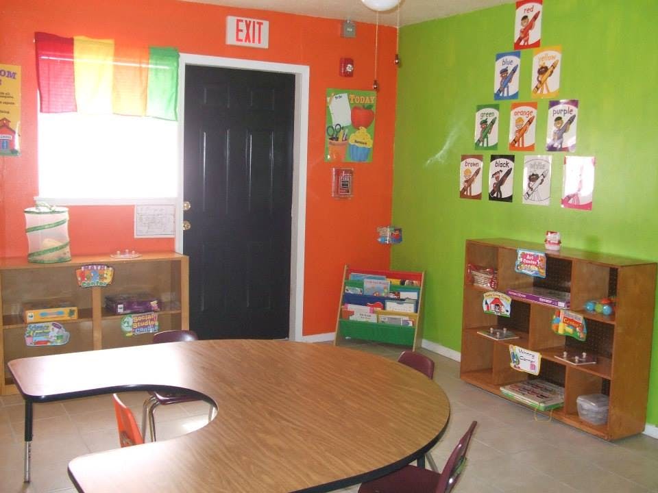 Classroom with orange and green walls, tables, and shelves