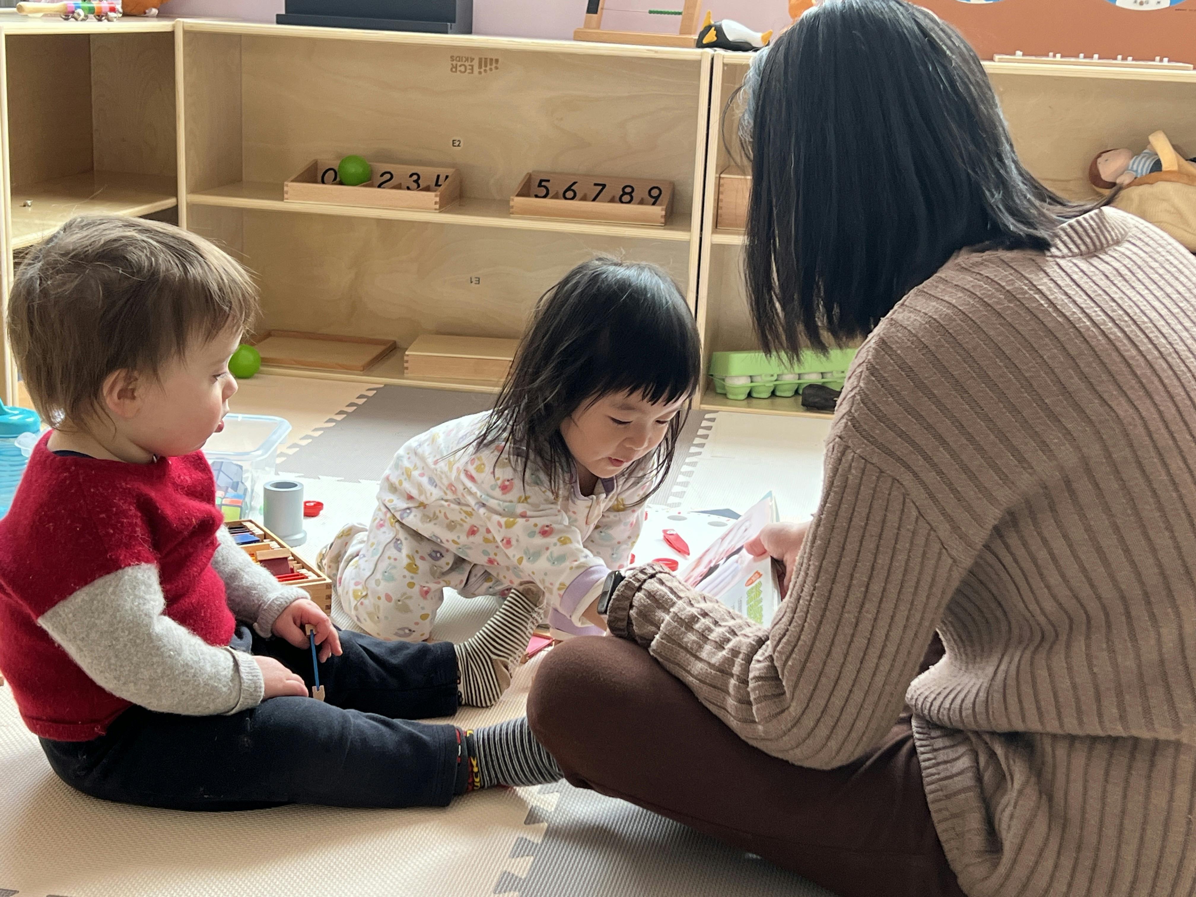 Adult and two children sitting on floor looking at a book