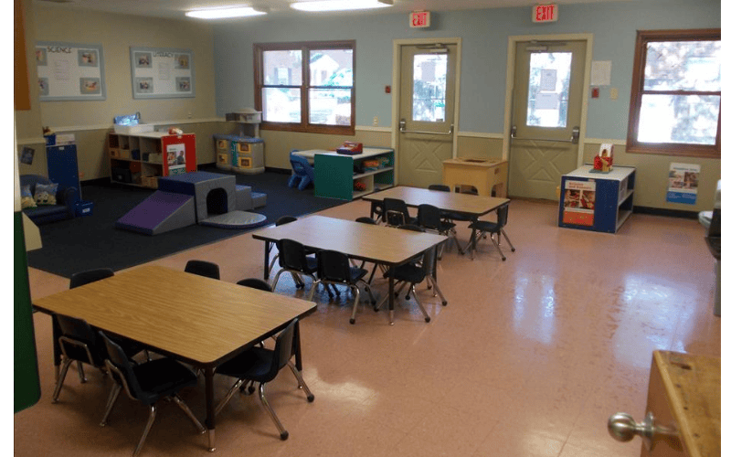 Empty preschool classroom with small tables and chairs
