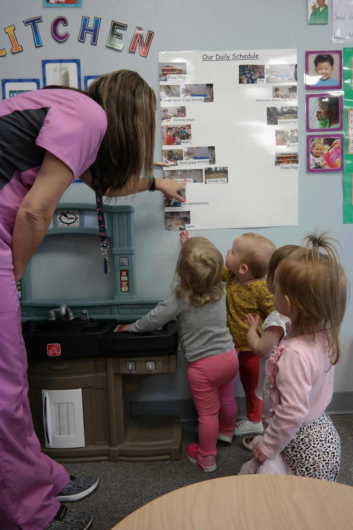 Person pointing to a schedule board with several children looking children