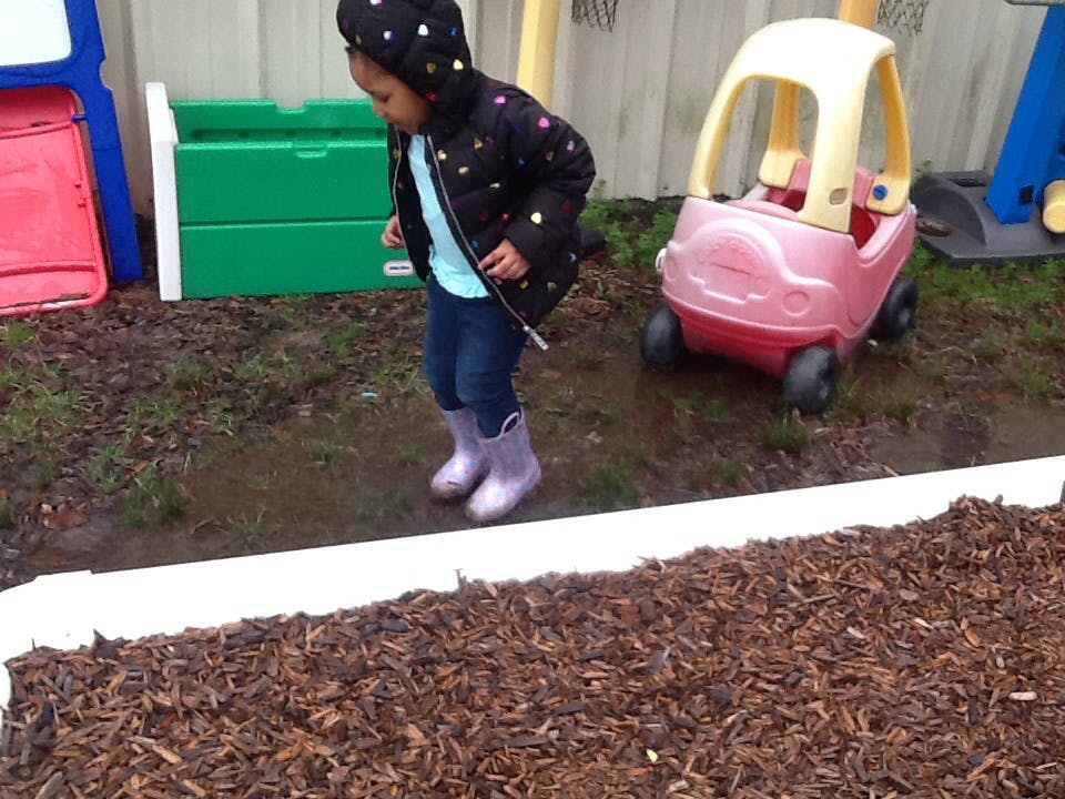 Child in a black jacket and boots standing in mud